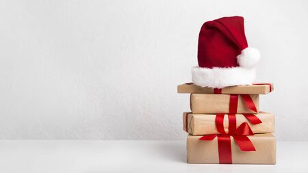 Happy New Year presents decorating by red ribbon with bow and Santa's hat on white background, panorama, copy spaceの写真素材