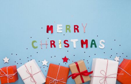 Creative Christmas background with present boxes and colored text on blue background, copy spaceの写真素材
