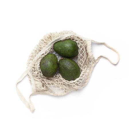 Save the planet. Fresh Avocado in eco bag for fruits and vegetables on whiteの写真素材