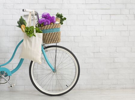 Clean the planet. Bicycle with wildflowers and organic food over white bricks wall background, copy spaceの写真素材