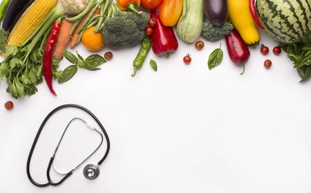 Healthy lifestyle without heart diseases. Stethoscope and organic vegetables isolated on white background, copy spaceの写真素材