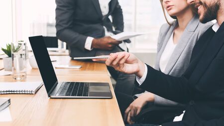 Colleagues discussing new project, poining on laptop at meeting, side viewの写真素材