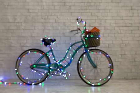 Santa's bicycle with presents and Christmas lights over white bricks wall, copy space, blurred backgroundの写真素材