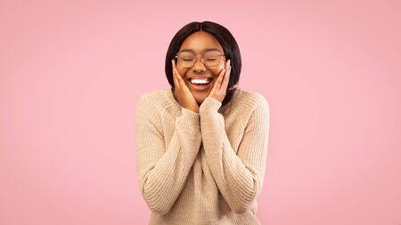 Joy. Happy Afro Girl Holding Hands On Cheeks And Smiling Standing Over Pink Studio Background....