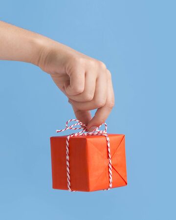 Close up of wrapped New Year box with presents in woman hand, blue background, copy spaceの写真素材