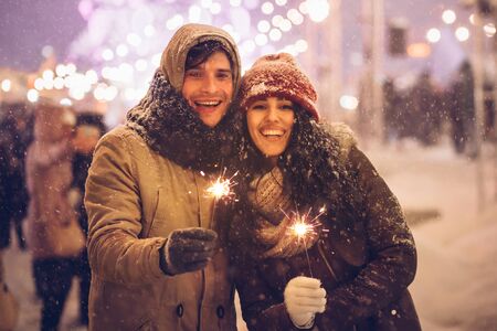 New Year. Happy Couple Holding Bengal Lights Celebrating Winter Holidays Standing Outdoor On...