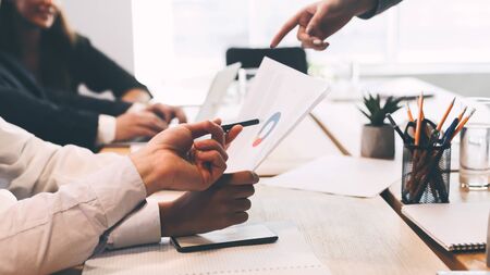 Young team working on business project with financial reports, discussing charts and diagramsの写真素材