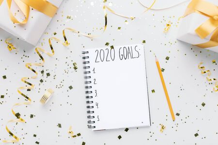 Happy new Year planning. Notebook with 2020 goals and gift boxes on white background, copy spaceの写真素材