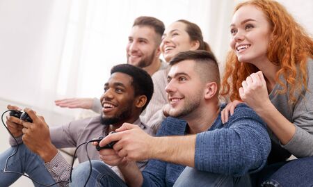 Diverse friends having fun and play video games together, competing online, panorama