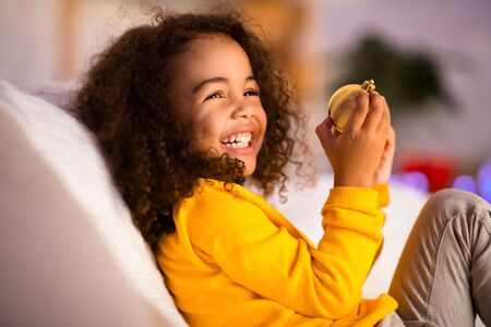 Cute african little girl playing with Christmas decorative ball