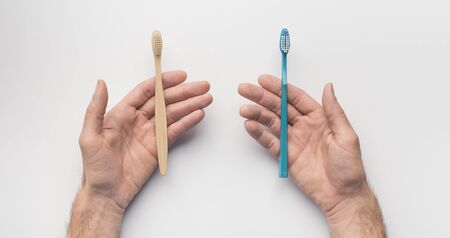Choose eco. Hands with two toothbrushes on white background, panorama