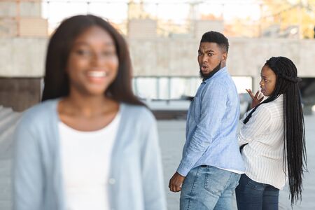 Unfaithful black womanizer guy turning around amazed at another woman while walking with his girlfriend on streetの写真素材