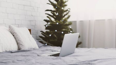 Christmas home interior with pine tree and open laptop on the bed, panorama, copy spaceの写真素材