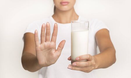 Lactose Intolerance Concept. Unrecognizable Woman Holding Milk And Gesturing No Standing In Studio On White Background. Croppedの写真素材