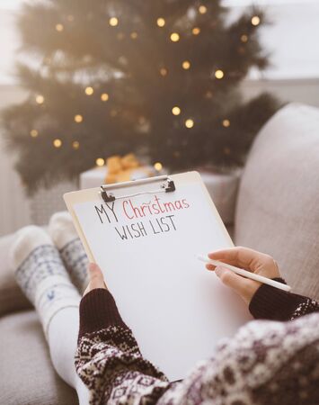 Woman creating Christmas wish list at home in funny clothes, blurred background, copy spaceの写真素材