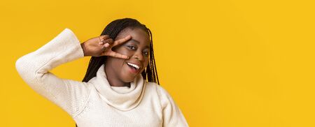 Portrait of playful african american girl posing over yellow studio background, panorama with copy spaceの写真素材