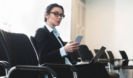 Businesswoman preparing for presentation, sitting in empty conference room with laptopの写真素材