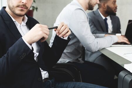 Young businessman with pen in hands on conference meeting looking at camera, cropの写真素材