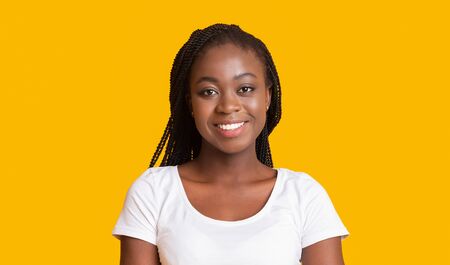 Portrait of young african american woman on yellow background with happy smile on her faceの写真素材