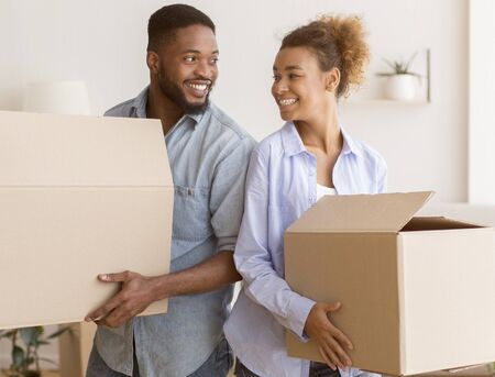 Happy Black Couple Holding Packed Boxes Smiling Each Other Standing Back-To-Back In New Homeの写真素材
