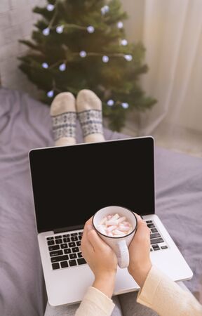 Female with mug of hot chocolate and open laptop with black blank screen, vertical panorama, copy spaceの写真素材