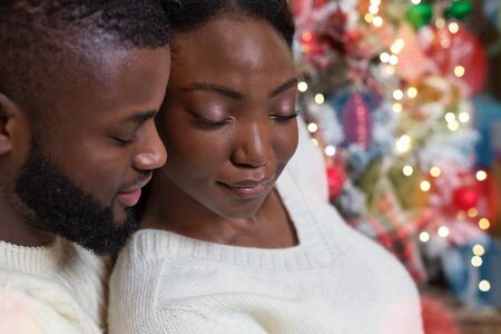 Young African american couple bonding with each other on Xmas eve, closing eyes in delight, closeupの写真素材