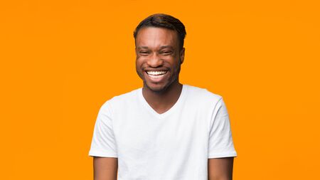 African American Guy Laughing Looking At Camera Standing On Orange Background. Panorama, Studio Shotの写真素材