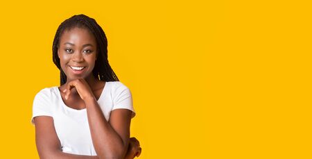 Excited black girl smiling at camera, touching her chin, panorama with copy spaceの写真素材