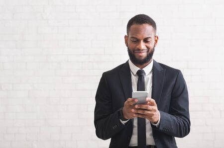 Happy african american businessman chatting on smartphone while having break, white background, copy spaceの写真素材
