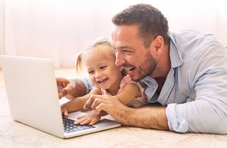 Family Time. Father and daughter making video call to mother using laptop on the floor. Copy spaceの写真素材