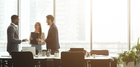 Successful businesspeople talking together in front of office windows, panorama, free spaceの写真素材