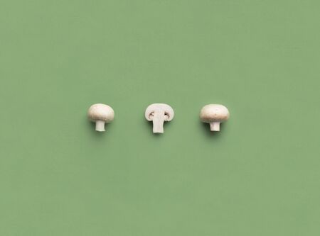 Creative vegetables concept. Slices of fresh mushrooms on green background, copy space