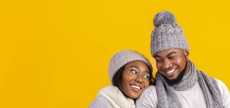 Black winter couple in love cuddling over yellow background, panorama with copy spaceの写真素材