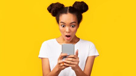 Human Reaction. Shocked african girl looking at phone seeing bad message. Panorama, free spaceの写真素材