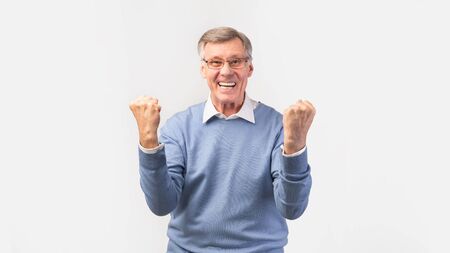 Winner. Excited Senior Man Shaking Fists Celebrating Victory Standing Over White Background. Studio...