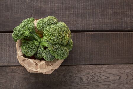 Green broccoli sprouts inside organic paper bag on wooden background, copy spaceの写真素材