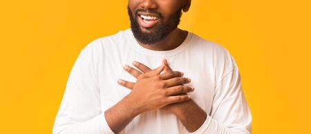 Cropped photo of african guy expressing his feelings, placing hands on chest, been touched with good...