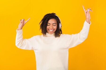 Favorite Music. Happy african american woman listening to music with headphones and dancing