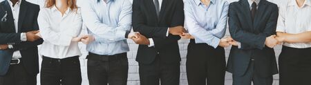 Synergy concept. Business team holding hands, standing in row on teambuilding courses, panoramaの写真素材