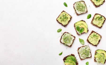Vegan toasts. Set of healthy sandwiches with tofu cheese, avocado and fresh microgreen on white,...