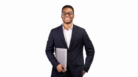 Business Person. Black manager in glasses holding laptop standing over white studio background. Copy...