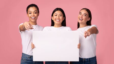 Offer For You. Three Millennial Girls Holding Blank White Board Advertising Something Standing Over Pink Studio Background. Mockup, Panoramaの写真素材