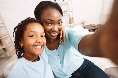 Self Portrait. Black family taking selfie, having fun together sitting on couch in the living roomの写真素材