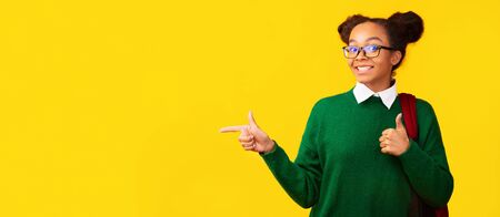 Best Choice. Excited afro teen girl pointing at copy space and showing thumbs up. Panorama, copy spaceの写真素材