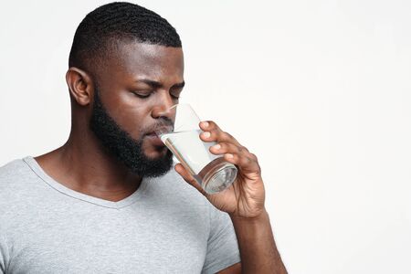 Thirsty young african man holding glass of drinking water for body health, healthy lifestyle, thirst...