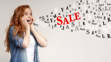 Unbelievable sales. Inscriptions Sale and diverse alphabet letters flying out of mouth of screaming redhead girl, light background, panoramaの写真素材