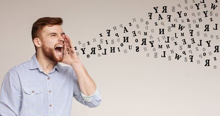 Shouting guy. Crazy emotional man screaming at copy space over grey background, diverse alphabet letters flying out of his mouth, panorama, free spaceの写真素材