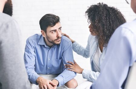 Depressed man getting some support from other patients of rehab group sessionの写真素材