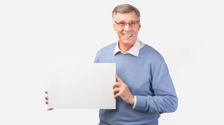 Smiling Senior Man Holding Blank Poster Board Advertising Great Offer Standing On White Studio Background. Mockup, Panoramaの写真素材