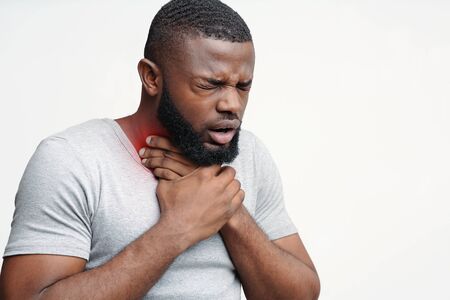 Unhealthy african man touching neck and coughing with closed eyes over white background, copy spaceの写真素材